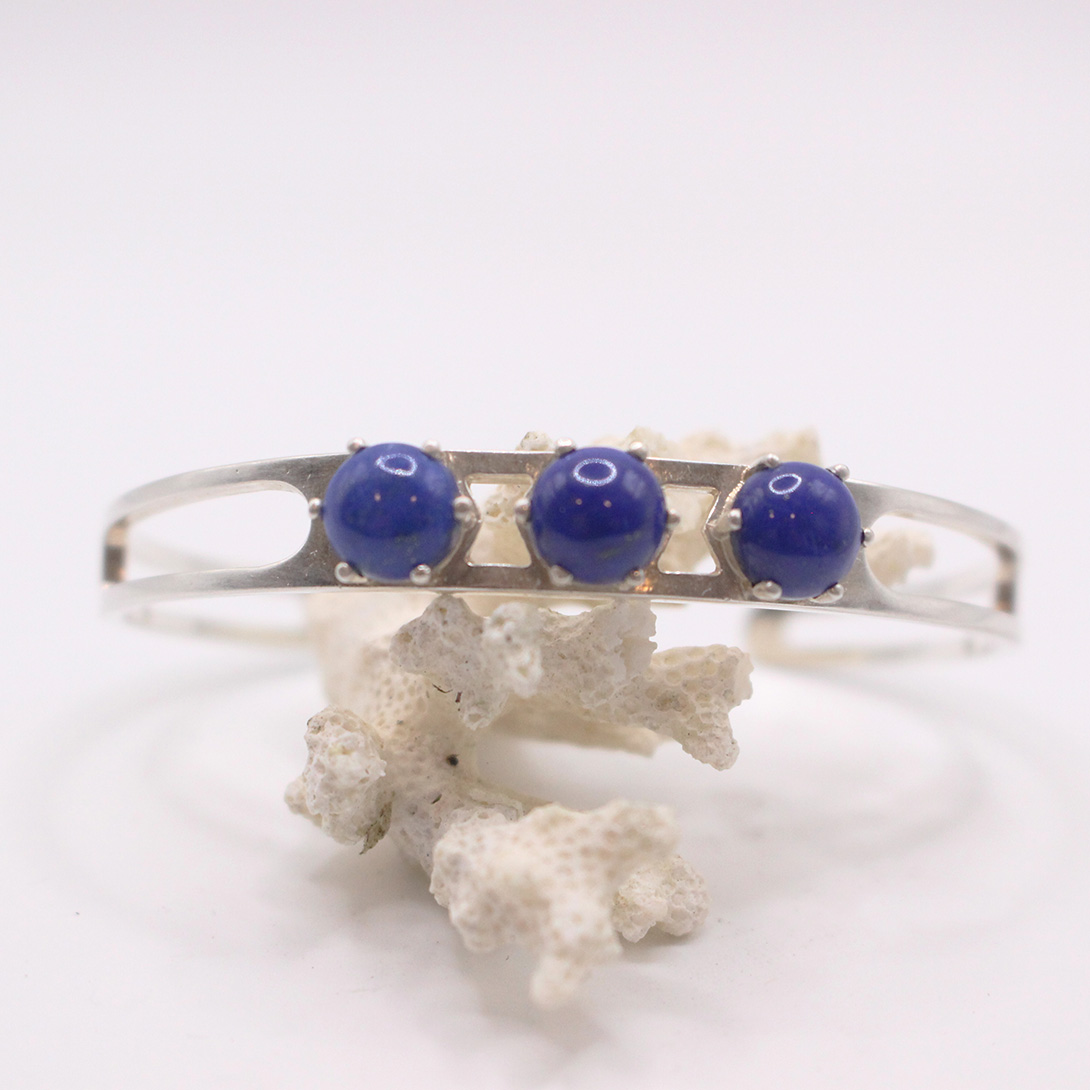 A silver bracelet with 3 blue stones on it.